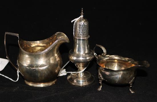 A George III silver cream jug, a similar cream boat and a small sugar caster